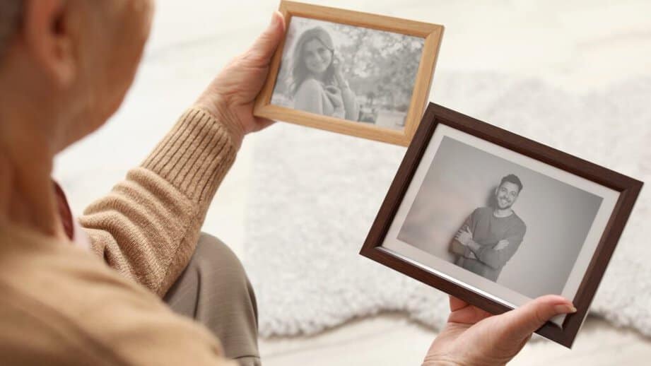 older woman looking at photos in pictures frames