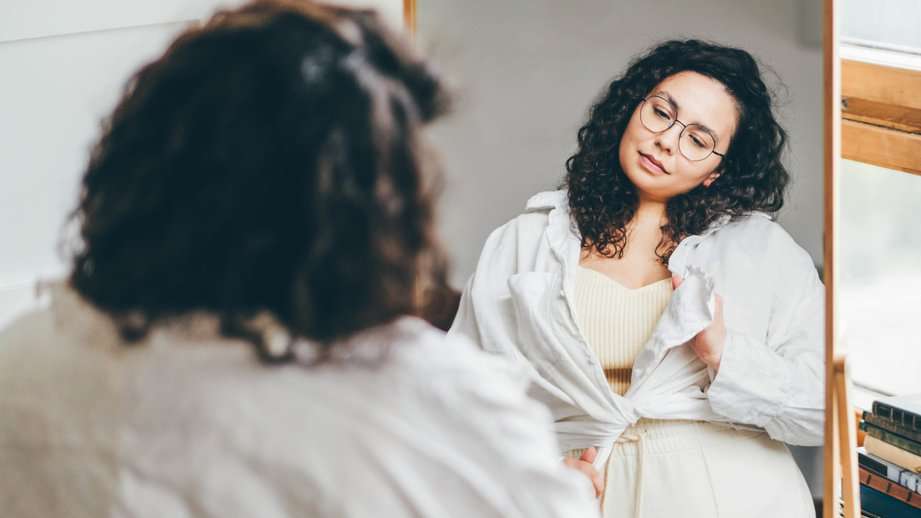 woman looking in mirror at her outfit