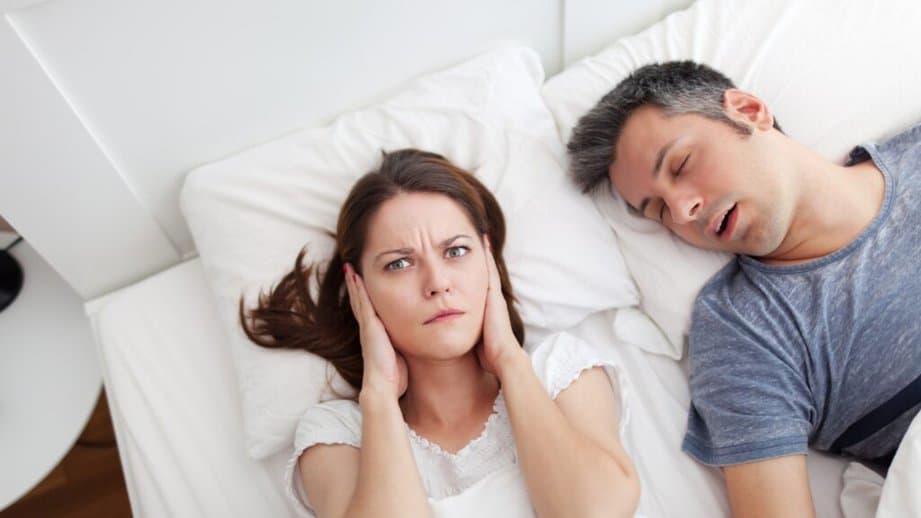 Man asleep with woman awake covering her ears