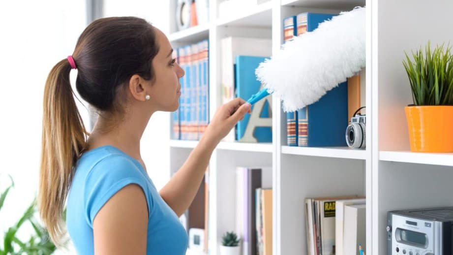 woman dusting a bookshelf