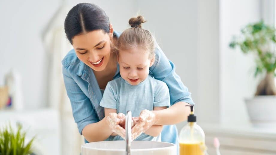 mother helping daughter wash hands