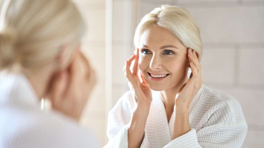 mature woman washing her face in the mirror