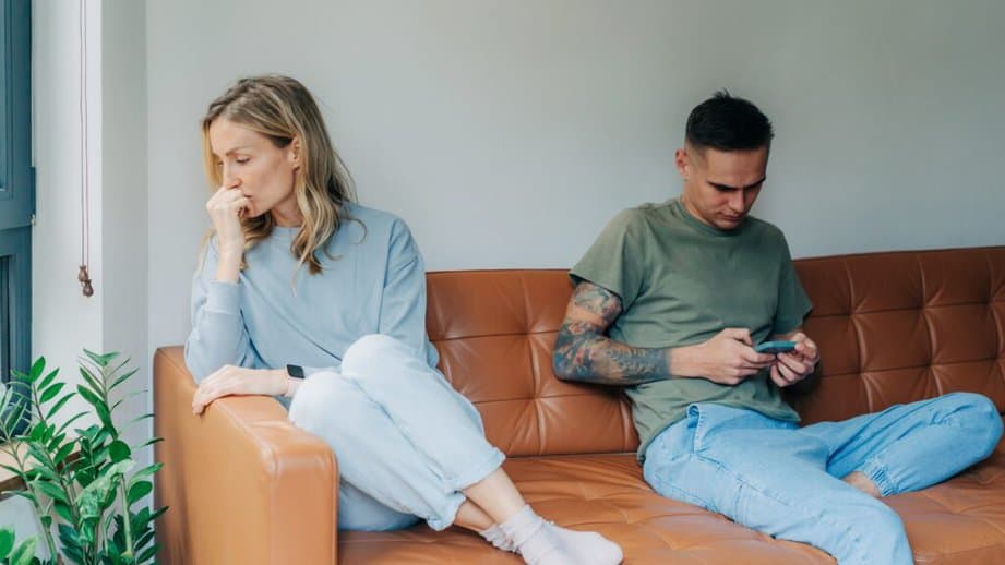 couple on a couch upset about man texting