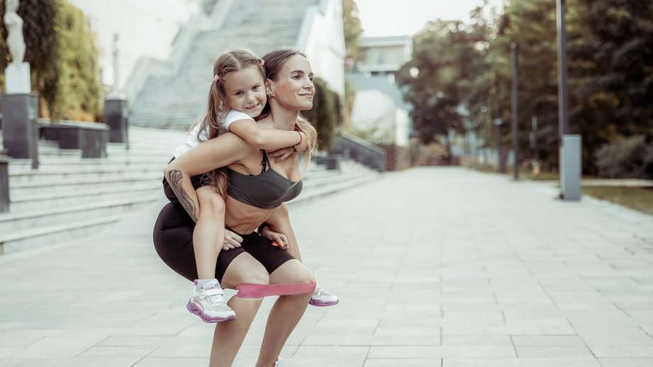 mom with daughter on back working out