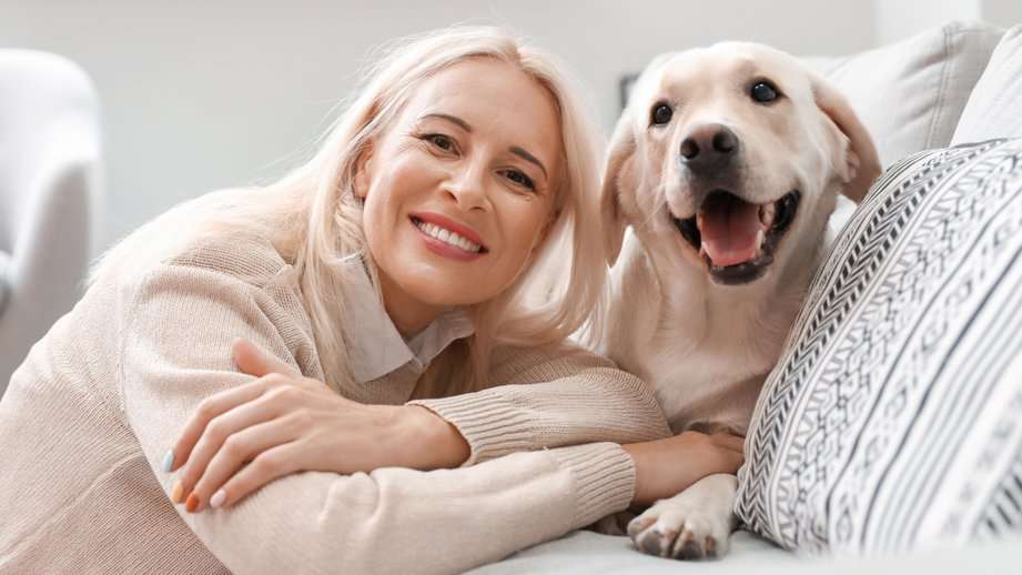 mature woman with dog on white couch