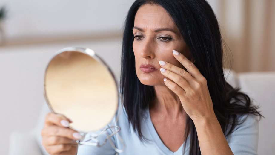 older woman looking in makeup mirror