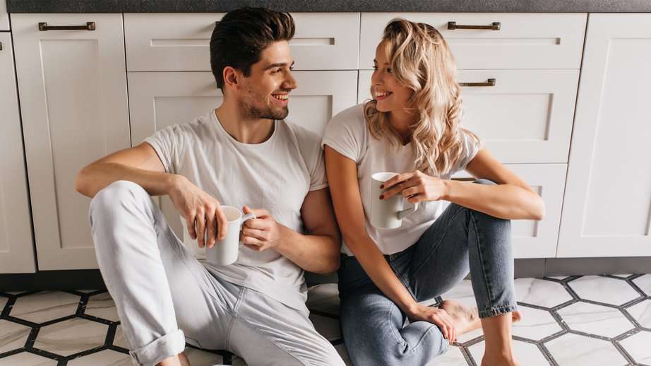 happy couple drinking coffee in the kitchen on the floor