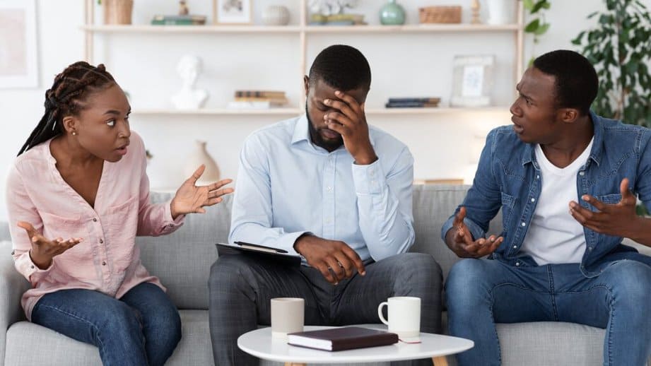 three adults sitting on a couch arguing