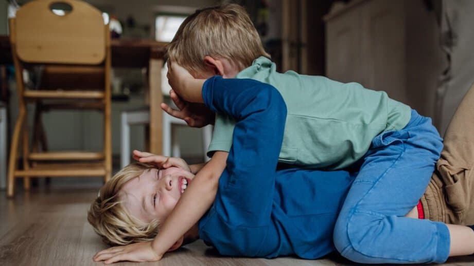 two little boys fighting on the floor