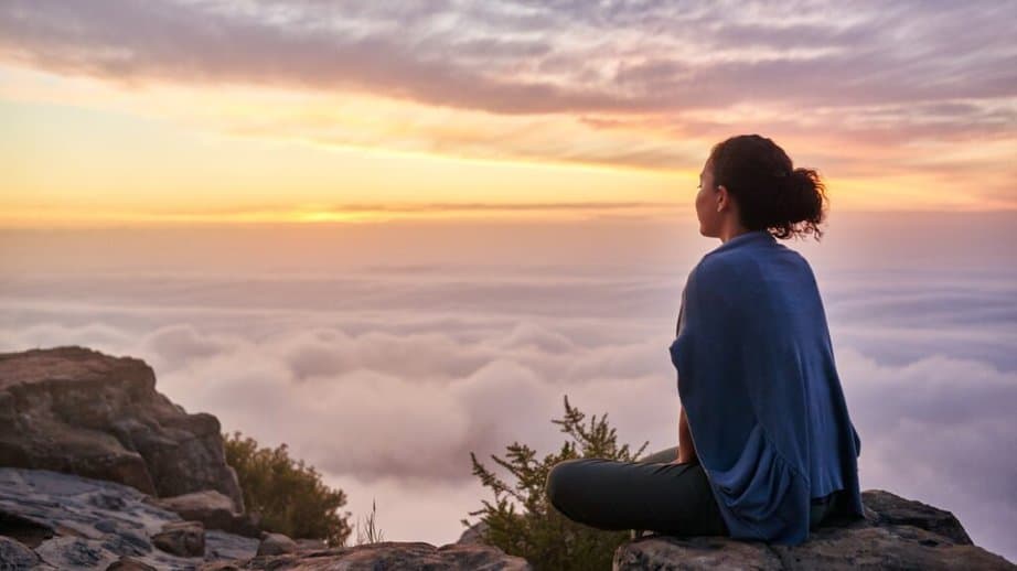 woman sitting on top of a mountail looking at the sunrise
