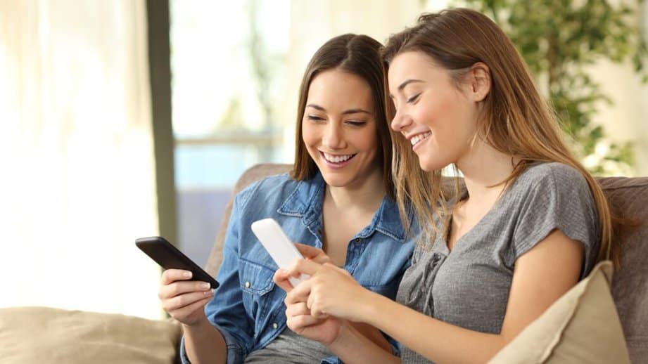 two girls on the couch looking at their phones