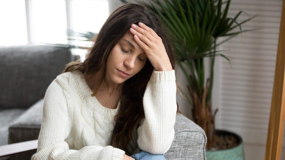 woman with her hand on her head stressed