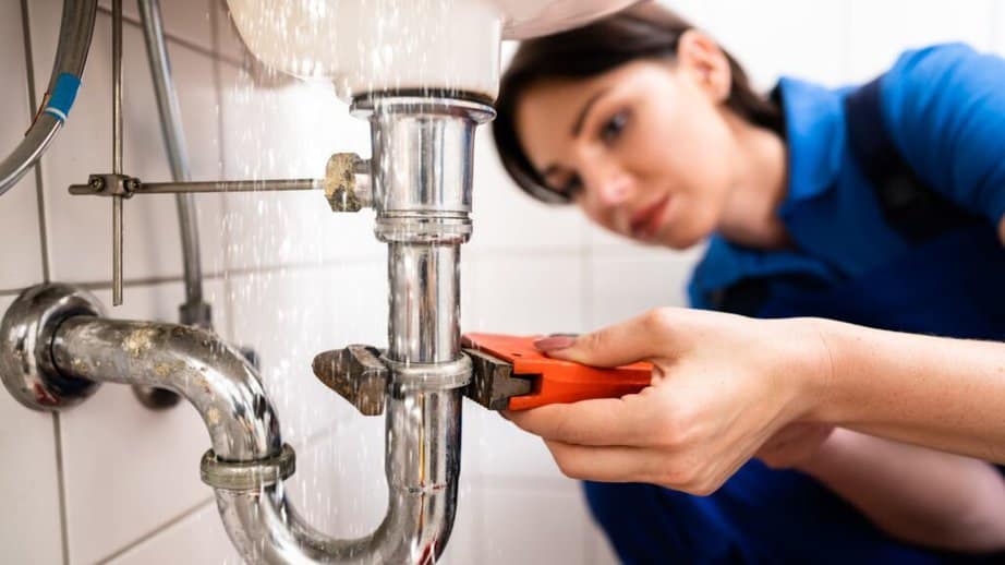 woman fixing a leaking pipe