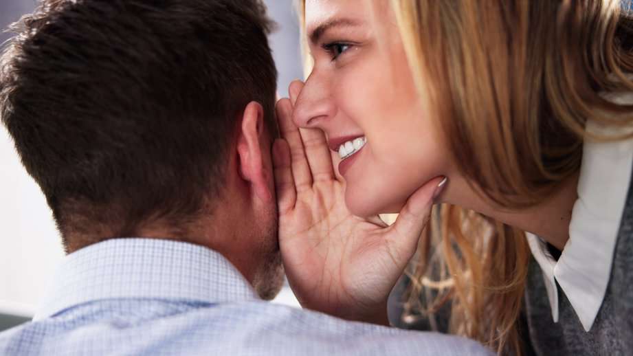 woman whispering in a mans ear smiling