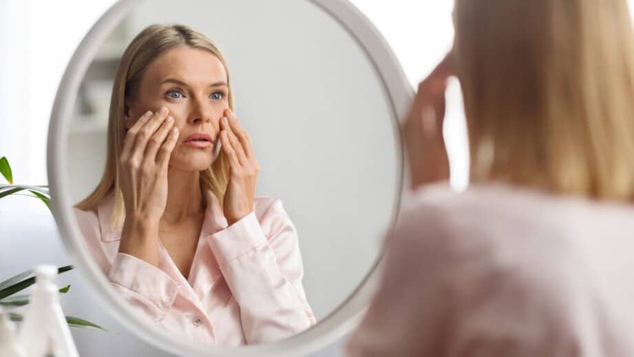 woman looking in mirror at complection