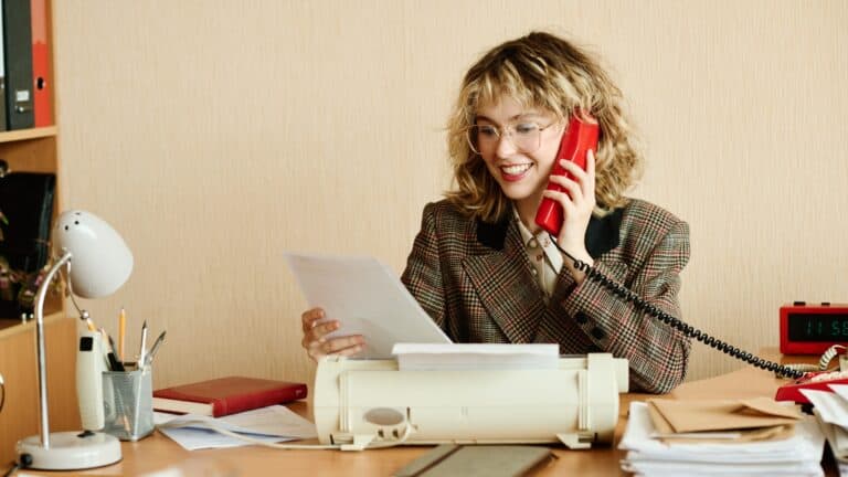retro woman on a rotary phone with a typewriter