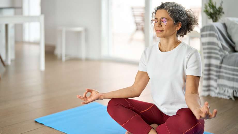 woman meditating on a mat in her home