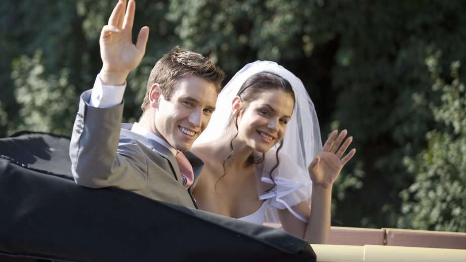bride and groom waving goodbye from a car